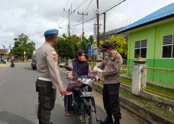 AKP Monang (kanan) pada saat membagikan masker kepada masyarakat setempat. F : mael/detak.media