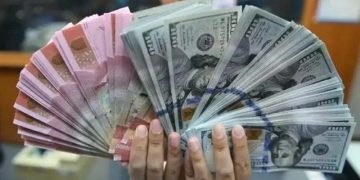 Ilustrasi: Teller menunjukkan lembaran rupiah dan dolar AS (ANTARA FOTO)