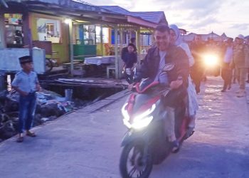 Tampak Bupati dan istri tengah mengendarai sepeda motor, sambil menyapa waraga