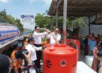 Pj Guburnur Jatim, Adhy Karyono (kanan) dan Pjs Bupati Blitar, Jumadi (kiri) bersama-sama menyalurkan air melalui selang ke tandon milik warga Desa Sumberkembar.